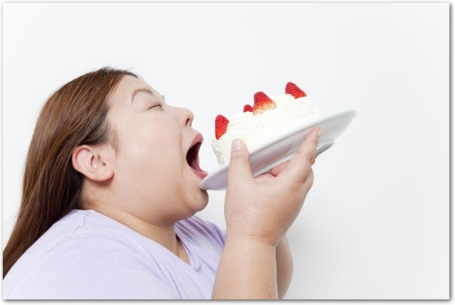 太った女性がホールケーキをそのまま食べようとしている様子